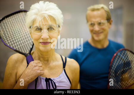 Porträt einer älteren Frau mit einem Squash Schläger beim Stehen mit ihrem Partner spielt. Stockfoto