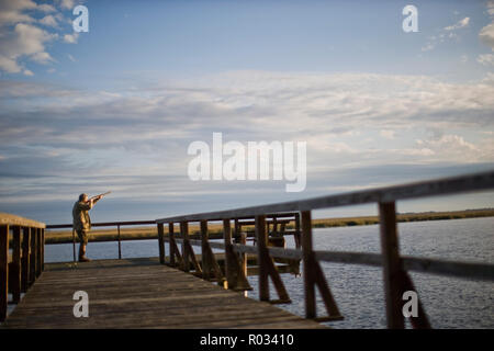 Mann stehend auf einem Wharf Holding ein Gewehr Stockfoto