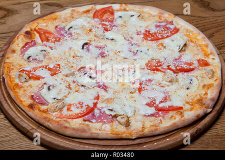 Pizza Milano cremige Basis, Hähnchenbrustfilet, Pilzen, Tomaten, Mozzarella, Oregano Sauce auf einer Platte Stockfoto