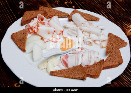 Eine Platte mit Snacks aus Speck und Croutons, Knoblauch und Zwiebeln. Drei Arten von Salat mit Croutons mit Knoblauch und Zwiebeln auf einer Platte Stockfoto