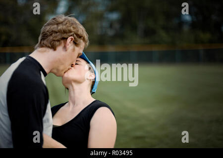 Junge erwachsene Paare küssen in der Nähe ein Sportplatz. Stockfoto