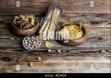 Snacks für Bier auf einer hölzernen Tisch. Chips, Croutons, Brot klebt und Pistazien Stockfoto
