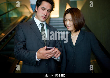 Kaufmann und Frau suchen nach etwas auf ein Handy. Stockfoto