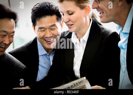 Mitte der erwachsenen Kollegen bei einer Zeitung lachen. Stockfoto