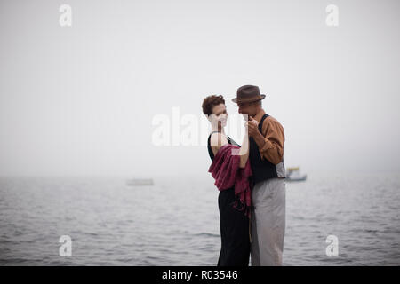 Lächelnde Paare tanzen in der Nähe von auf das offene Meer auf einem nebligen Tag. Stockfoto