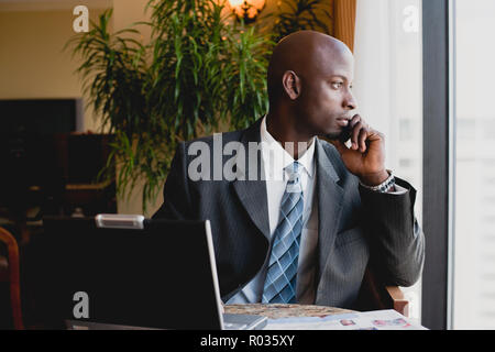 Mann mit Handy mit Laptop Stockfoto