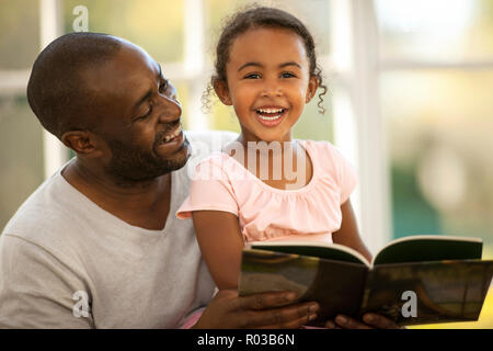 Lächelnd Vater und Tochter in einem Buch zusammen. Stockfoto