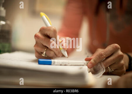 Hände von einer Ärztin schreiben auf einen medizinischen Test Tube mit einem Stift. Stockfoto