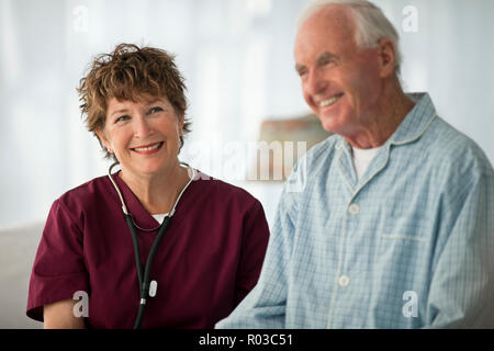 Lächelnd reife Krankenschwester sitzend mit einem älteren Patienten. Stockfoto