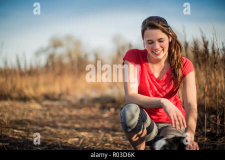Lächelnde junge Frau nimmt einen Bruch von ihrer Landschaft laufen am späten Nachmittag Sonne. Stockfoto