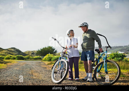 Gerne ältere Paare zusammen plaudern, als sie eine Pause vom Radfahren entlang einer Landstraße.