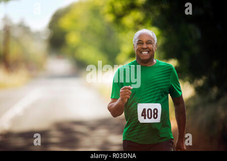 Porträt eines lächelnden reifer Mann joggen auf einer Landstraße. Stockfoto