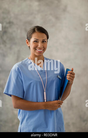Porträt eines lächelnden jungen Krankenschwester eine Zwischenablage. Stockfoto