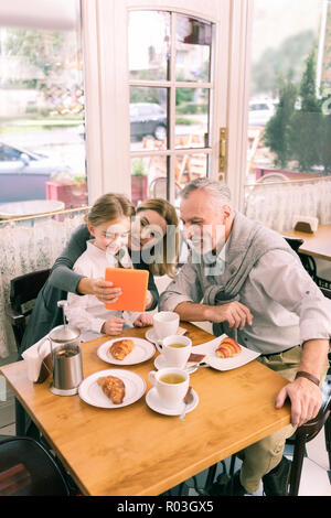 Glücklich strahlenden Großeltern essen Morgen Croissants mit Enkeltochter Stockfoto