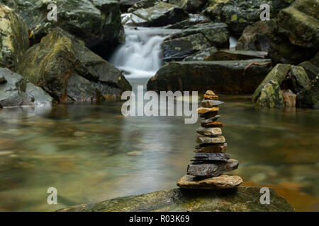 Verschiedene geformte Zen Steine gegen einen Wasserfall Hintergrund gestapelt Stockfoto