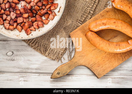 Gebratene Würstchen in Scheiben in einem Würfel auf einer Pfanne auf einem hölzernen Hintergrund. Stockfoto