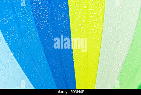 Bunt wie ein Regenbogen Regenschirm mit Tropfen von Wasser, wenn es regnet, Nahaufnahme in der Natur Stockfoto