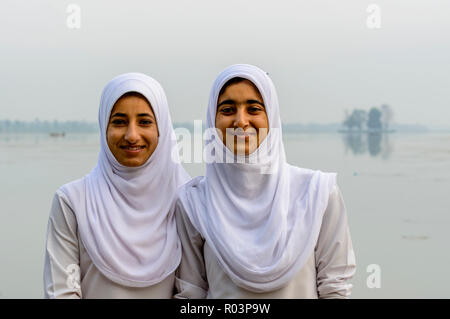 Ein Porträt von zwei Kaschmirischen Schule Mädchen in ihrer Schule Kleid, über ihren Köpfen von weißen Schals Stockfoto