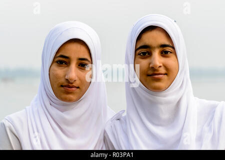 Ein Porträt von zwei Kaschmirischen Schule Mädchen in ihrer Schule Kleid, über ihren Köpfen von weißen Schals Stockfoto