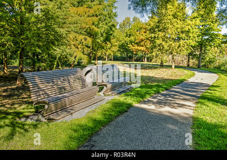 Utrecht, Niederlande, 27. September 2018: zwei hölzernen Bänken entlang führt ein Fußpfad schlängelt sich durch Wiesen und Baumgruppen in Maximapark im Herbst Stockfoto