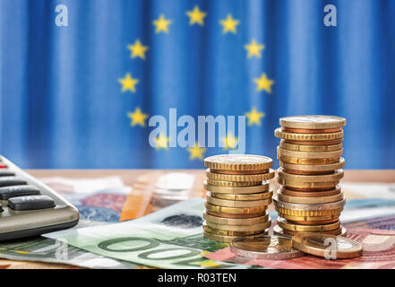 Banknoten und Münzen vor der Flagge der Europäischen Union Stockfoto