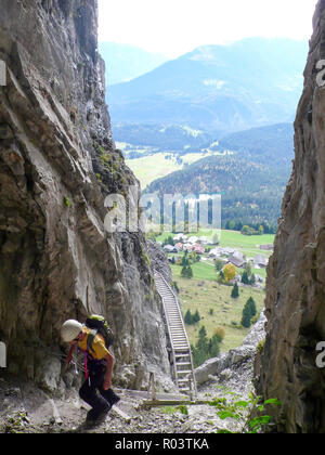 Berg Kletterer klettern über eine steile, felsige Schlucht auf dem Weg zu einer hochalpinen Gipfel mit einem tollen Blick hinter ihm in den Schweizer Alpen Stockfoto