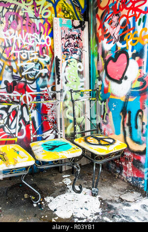 Bemalte Stühle vor grafitti bedeckte Wand Stockfoto