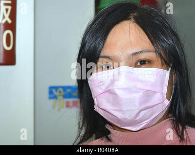 Junge Taiwanesische vegetarische cookee und Kellnerin mit lächelnden Augen trägt ein rosa Einmal-OP-ohrläppchen Gesichtsmaske. Stockfoto