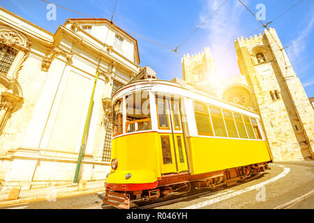 Historische gelbe Tram der Linie vor der Kathedrale von Lissabon, Alfama, Lissabon, Portugal. Lissabon Straße mit typischen vintage Straßenbahn- und Se de Lisboa. Abendlicht erschossen. Stockfoto