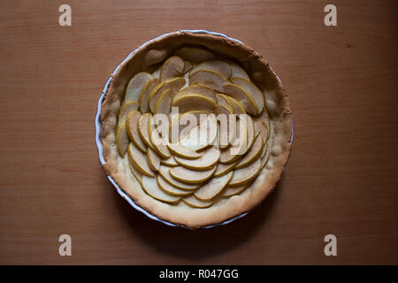 Halbe gebackene Torte mit in Scheiben geschnittenen Äpfel in floralen Rosettenform auf Holzbrett aus einem hohen Winkel anzeigen isoliert gefüllt Stockfoto