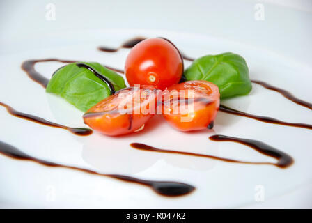 Tomaten, Basilikum und Balsamico Essig auf eine weisse Platte Stockfoto