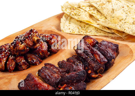 Bier Snack auf der Holzplatte. gegrillte Schweinerippchen und Chicken Wings mit italienischen pita Brot Chips Stockfoto