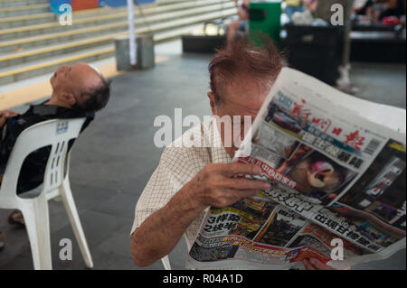 Republik Singapur, Mann liest Zeitung in Chinatown Stockfoto