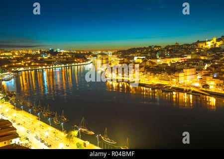 Rabelo und touristische Boote auf dem Fluss Douro. Porto Nachtleben von Oporto Skyline und Ribeira Waterfront von Dom Luis I Brücke bei Nacht. Malerische Stadt Stadtbild von Porto in Portugal. Stockfoto