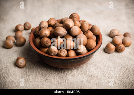 Haselnüsse in eine Schüssel mit glasiertem Steingut auf einem Leinentuch. Stockfoto