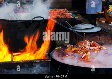 Hecha, Ukraine - Jan 27, 2018: Schweinefleisch Metzger Wettbewerb. kochende Kessel in Brand. Fleisch kochen auf dampfenden Teller. Leer, Grill in der Ferne Stockfoto