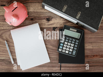 Datei Ordner, Notizen, Rechner und Sparschwein auf Tisch Stockfoto