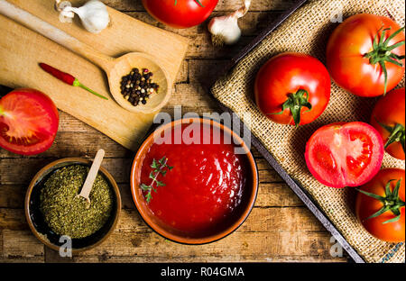 Tomaten und Tomatenmark auf einem rustikalen Holztisch, Ansicht von oben Stockfoto