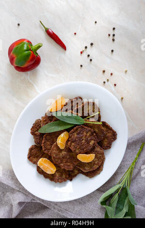 Lecker Leber Koteletts mit Mandarinen auf einem weißen Teller auf dem Tisch. Ansicht von oben. Stockfoto