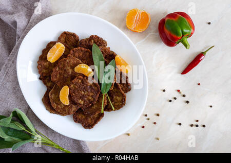 Lecker Leber Koteletts mit Mandarinen auf einem weißen Teller auf dem Tisch. Ansicht von oben. Stockfoto