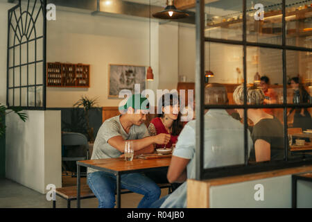 Vielfältige Gruppe von Freunden, die zusammen essen in einem Bistro Stockfoto