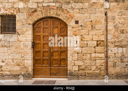 Alte kunstvolle Holz- dooor der antiken Gebäude aus Stein, hoch liegende Stadt San Gimignano, Toskana, Italien Stockfoto