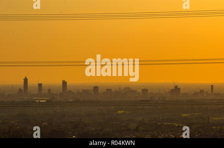 Der Himmel erscheint gelb, wie die Sonne über grössere Manchester an einem nebligen Abend Stockfoto