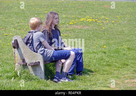 Zwei Jungen im Teenageralter sprechen auf einer Bank Stockfoto