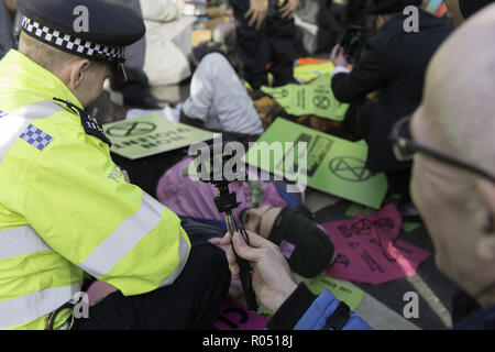 London, Greater London, UK. 31 Okt, 2018. Umweltaktivisten werden gesehen, liegen in der Mitte der Straße rund um den Parliament Square während des Protestes. Die neu gebildete Aussterben Rebellion Gruppe, besorgt über Klimawandel, fordert eine friedliche massenhaften zivilen Ungehorsam Politik Engagement und Handeln in Bezug auf Umweltfragen zu markieren. Aktivisten im Parlament Platz versammelt und blockierten die Straße für zwei Stunden. Der Protest enthalten Lautsprecher wie Greta Thunberg, Caroline Lucas, und George Monbiot. Nach Aussterben Rebellion 15 Menschen wurden Stockfoto