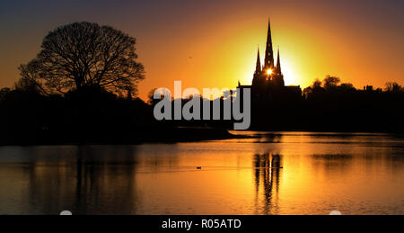 02/11/18 Vor einer kalten Nacht, die Sonne scheint durch die zentralen Turm der Kathedrale von Lichfield, und ist in Stowe Pool wider. Die Staffordshire mittelalterliche Kathedrale ist die einzige englische Kathedrale mit drei Türmen. Die drei Türme werden oft als die Damen der Vale' bezeichnet. Stockfoto