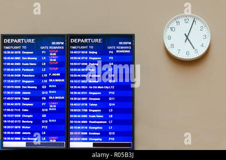 Flughafen Information Board, in der Nähe der Uhr mit Händen, die vier Minuten nach fünf Shows, Flugplan. Malaysia, Kuala Lumpur, KLIA 2. Stockfoto