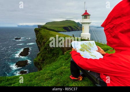 Wanderer auf Klippen sieht auf der Karte neben dem Leuchtturm, Mykines Island, Färöer, Dänemark Stockfoto