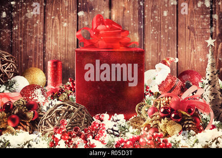 Weihnachten Geschenk Box in der Mitte von Christbaumschmuck auf hölzernen Planken vorgestellt Stockfoto