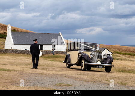 Eine 1935 im klassischen Rolls Royce 20/25 wartet in der Nähe der Heilig-Kreuz-Kirche (Eglwys Y Grog), während es Chauffeur steht in der Nähe von. Mwnt, Ceredigion, Wales Stockfoto